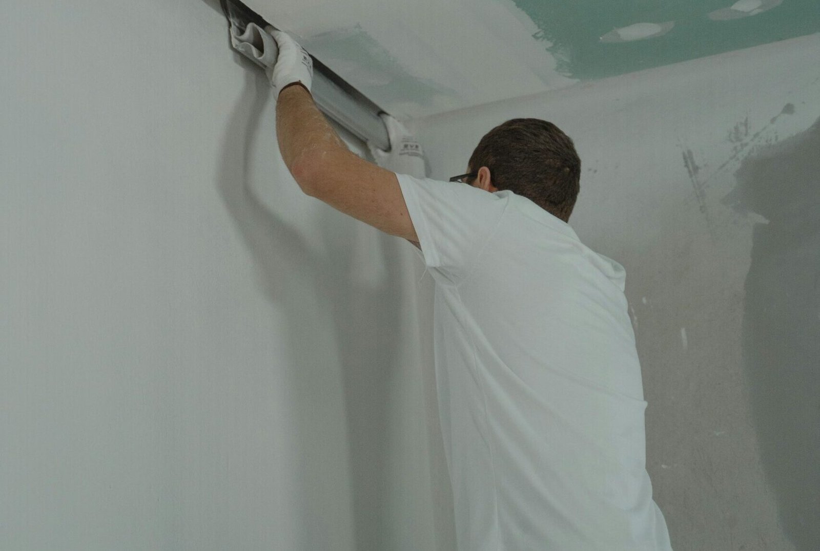 A man works meticulously on drywall installation during a house renovation.